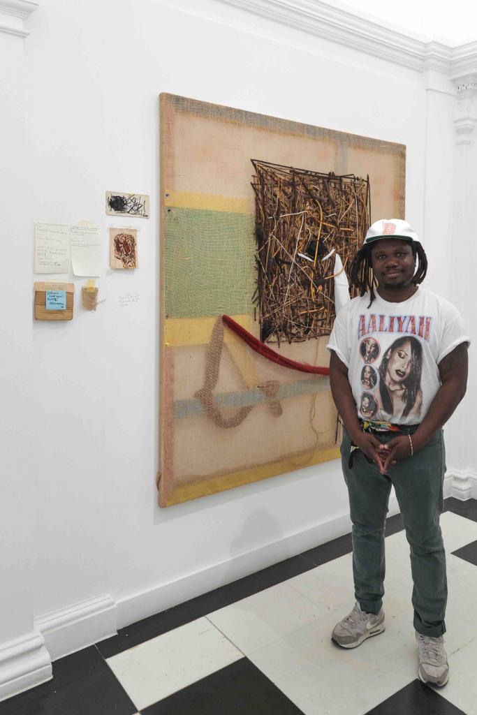 Artist Alvaro Barrington in front of his artwork, Unc you the plug, 2019 Mixed media on burlap. During the exhibition "Artists I steal from" at Thaddaeus Ropac Gallery © Thaddaeus Ropac Gallery