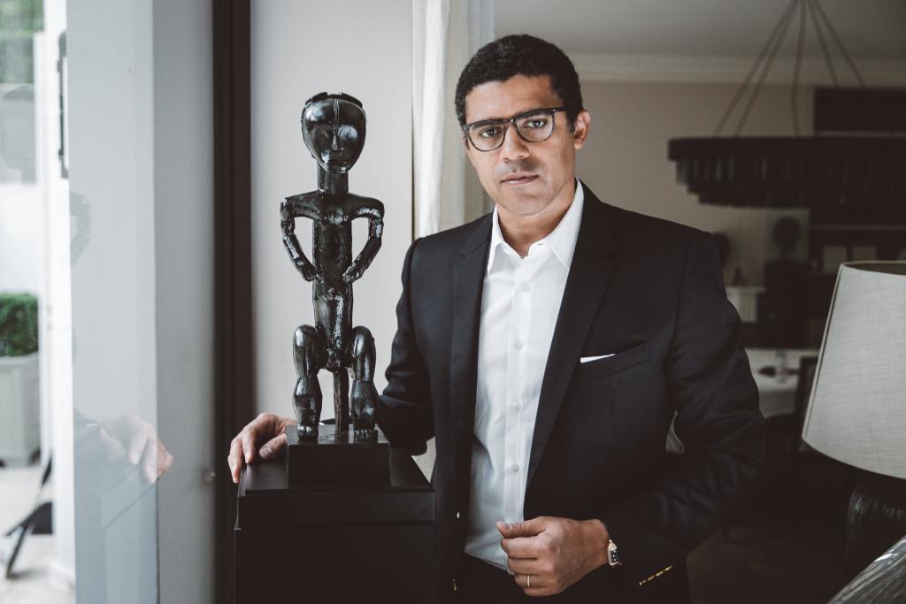 Sindika Dokolo (°1972, Kinshasa) est un collectionneur d’art et mécène, qui se partage entre l’Angola, le Congo, Porto, Londres et Bruxelles. Il est l’un des collectionneurs les plus renommés d’Afrique et possède l’une des collections les plus vastes : près de 5 000 pièces d’art classique et contemporain africain. En 2007, il a créé la Sindika Dokolo Foundation, une organisation sans but lucratif dont l’objectif est de soutenir et d’encourager le développement de l’art contemporain d’Afrique et de la diaspora. Cette fondation vise à augmenter la visibilité de l’art africain, sur le continent lui-même mais aussi au niveau international. La Sindika Dokolo Foundation a ainsi conçu et créé le premier pavillon africain à la 52e Biennale de Venise et soutenu les artistes africains qui ont participé à Documenta 14, à Kassel. Sindika Dokolo contribue aussi activement au débat concernant le rapatriement d’objets d’art volés. Une mission de restitution est d’ailleurs en cours, qui a déjà permis de retrouver et de récupérer quelques œuvres volées au musée Dundo, en Angola.