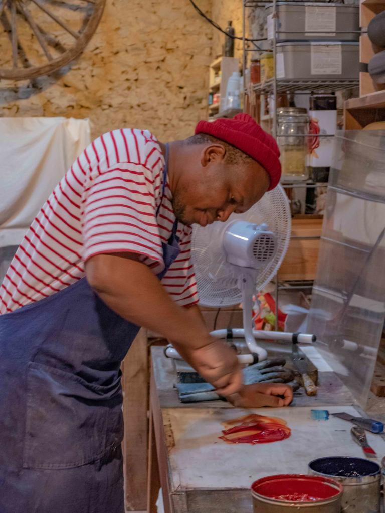 Mongezi Ncaphayi en train de mélanger les pigments de couleur pour obtenir la nuance parfaite pour sa prochaine oeuvre.