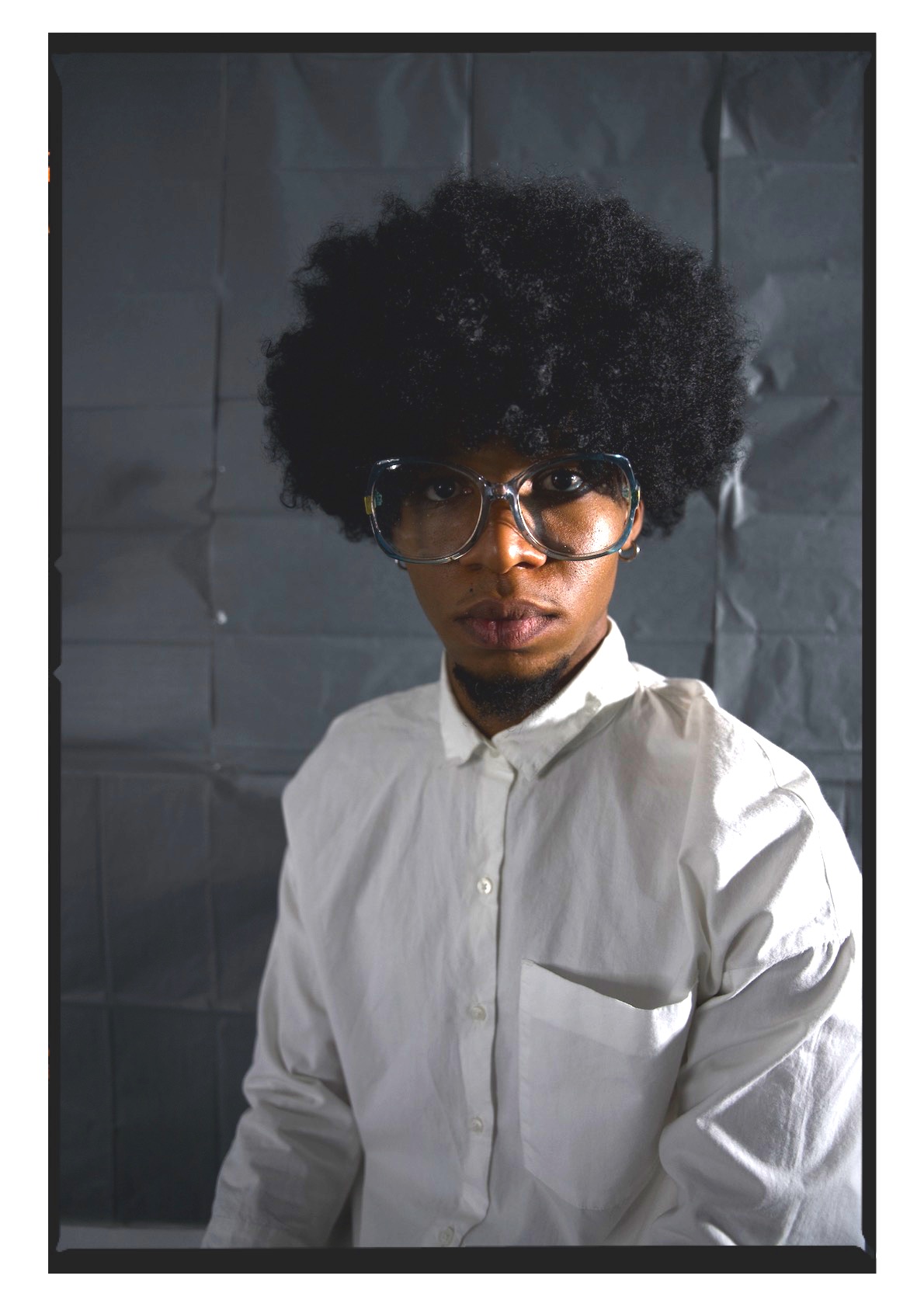 K.Skits wears an afro symbolising blackness and a white shirt as commentary on the sanitisation of blackness he says artists are often cornered into by the palatability requirements of the white gaze.